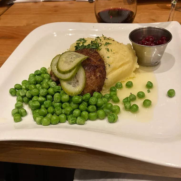 Panerad biff med potatismos, gröna ärtor, rårörda lingon och inlagd gurka